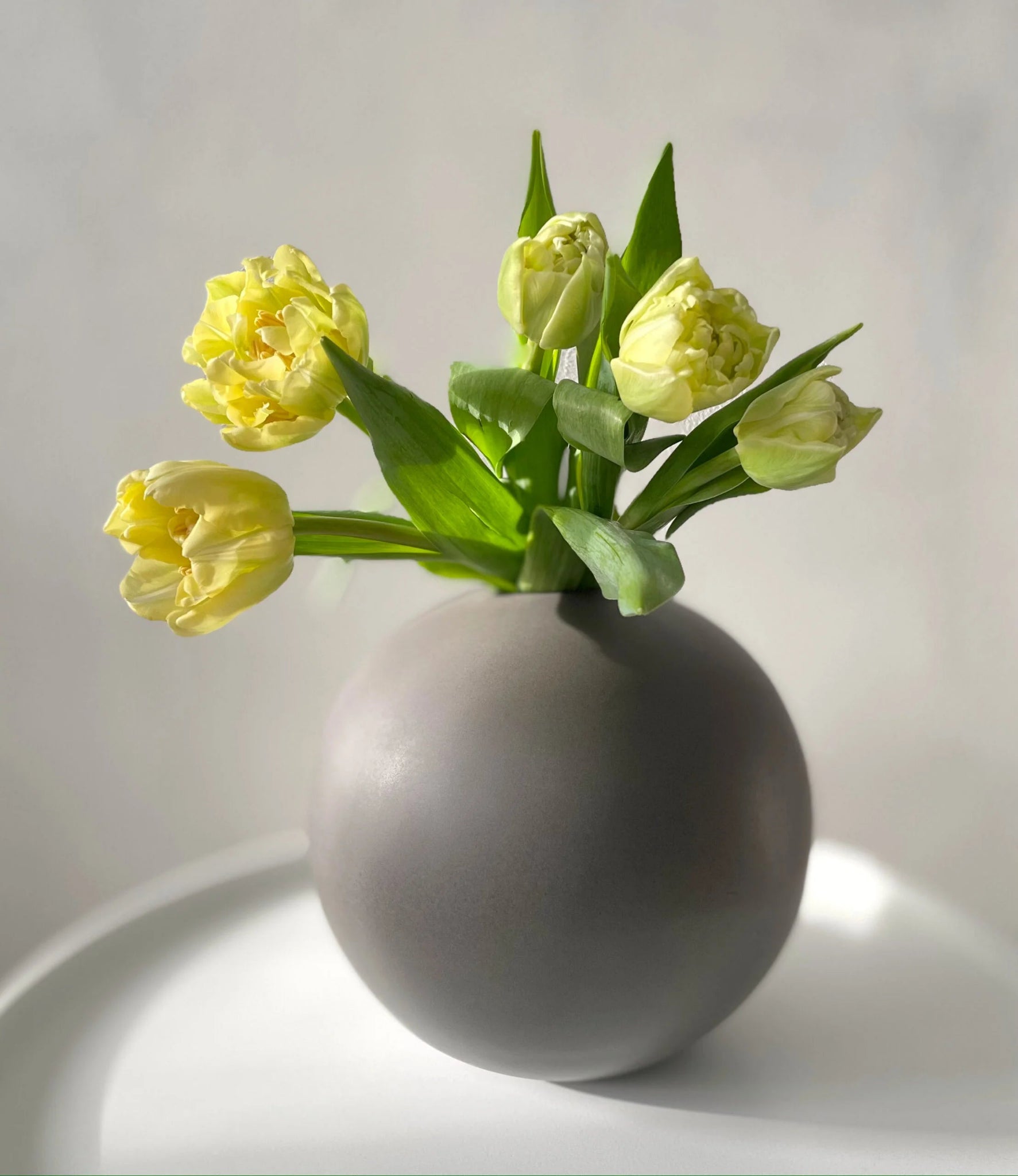 Pallo-maljakko keskikoko harmaa kukkien kanssa pöydällä