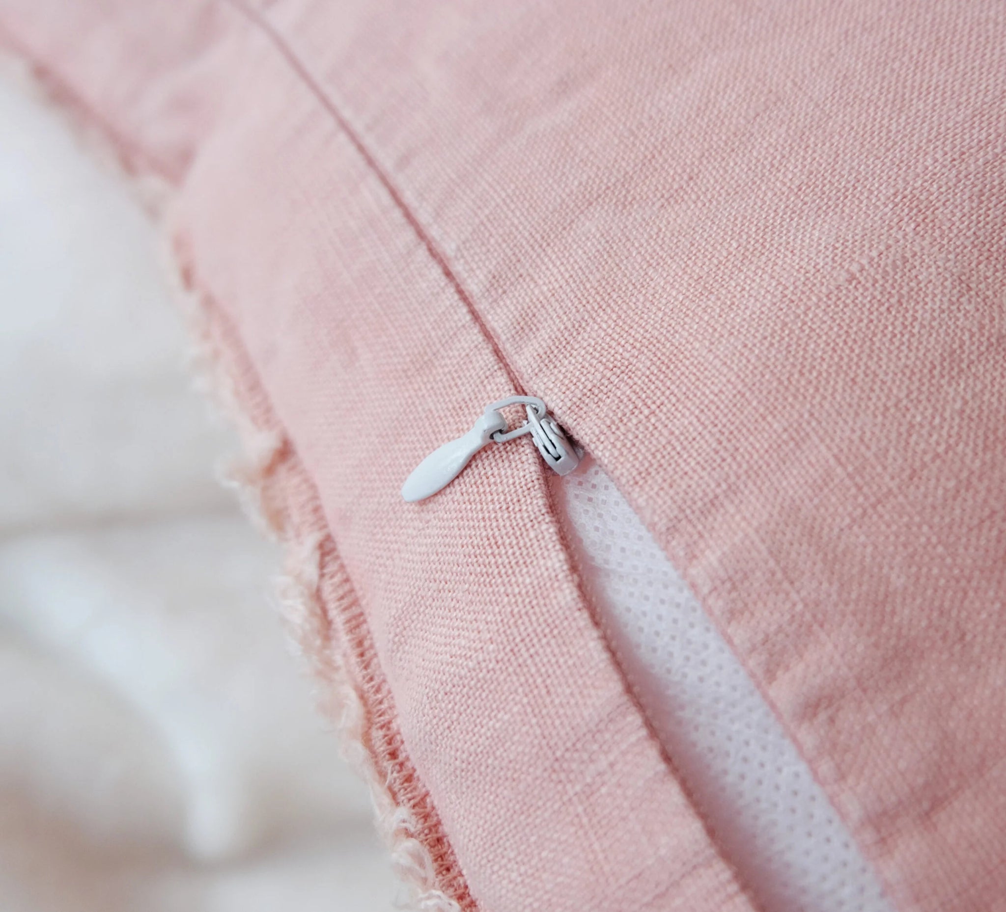 Lähikuva Peach Pink -tyynyn vetoketjusta – pellavainen reunahapsu detalji