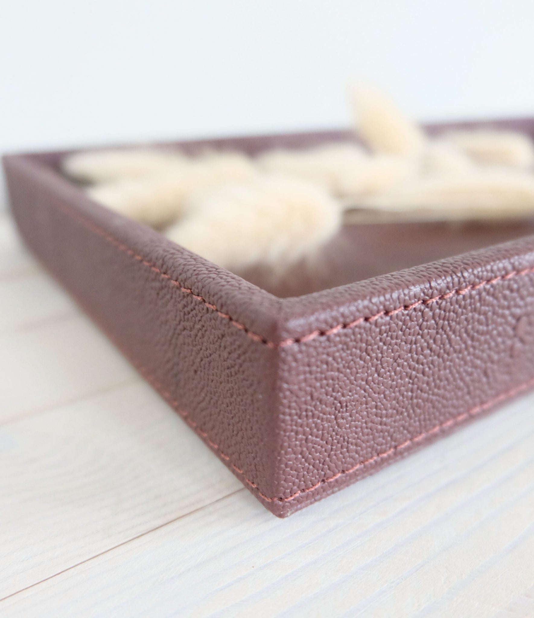 Lähikuva Sting-tarjottimen viininpunaisesta keinonahkapinnasta